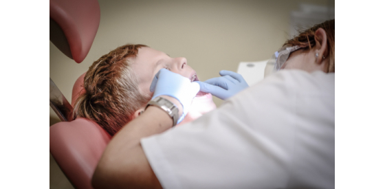 Dentist looking into a child patient's mouth to check his teeth