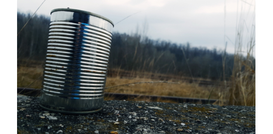 Aluminium can on a street with natural scenery in the background.