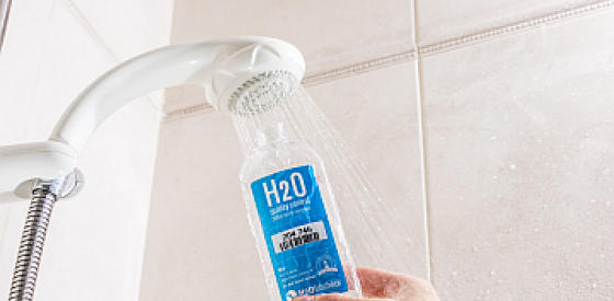 Hand holding Water sampling bottle under showerhead